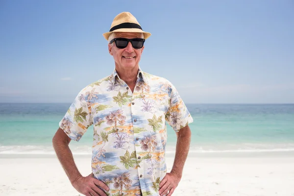 Senior man in zonnebril en hoed staande op strand — Stockfoto