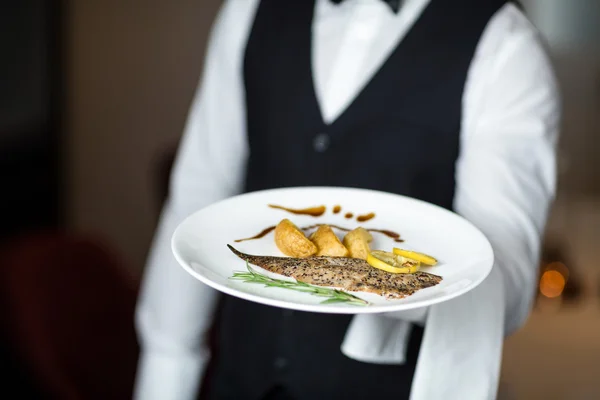 Handsome waiter presenting meal — Stock Photo, Image