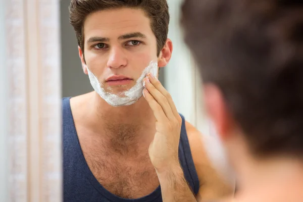 Homem aplicando espuma de barbear no rosto — Fotografia de Stock