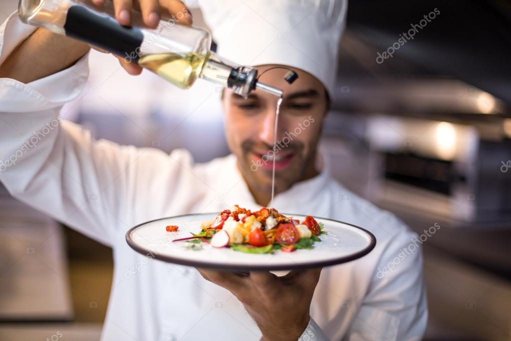 Handsome chef pouring olive oil on meal — Stock Photo © Wavebreakmedia