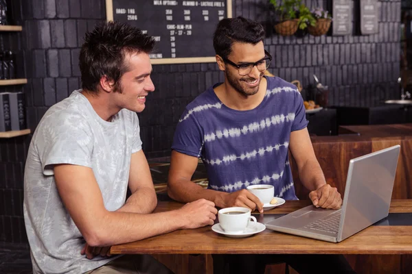 Amigos usando um laptop enquanto conversam — Fotografia de Stock