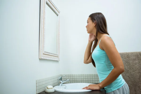 Woman checking skin in bathroom — Stock Photo, Image