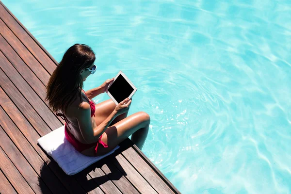 Femme utilisant une tablette sur le bord de la piscine — Photo