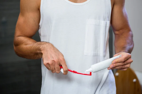 Adam üzerinde diş fırçası Diş macunu sıkma — Stok fotoğraf