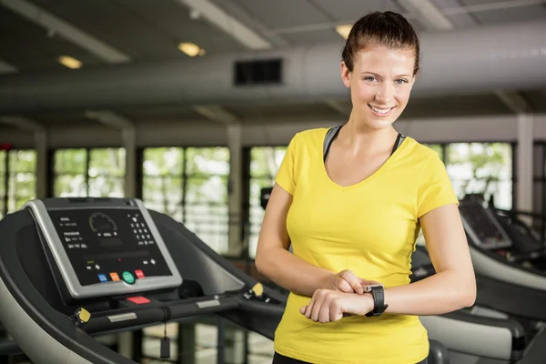 Vrouw met behulp van slimme horloge op loopband — Stockfoto