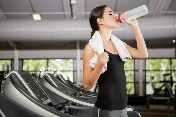 在健身房的跑步机上喝水的女人 — 图库照片