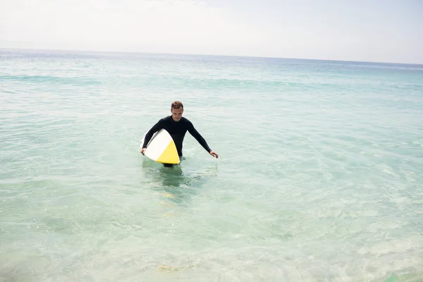 Surfista caminando en la playa con tabla de surf —  Fotos de Stock