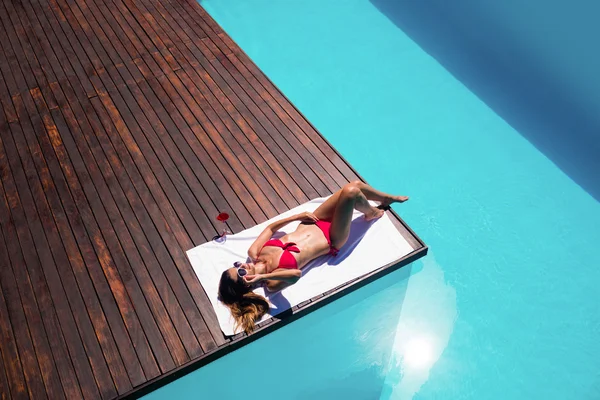 Mujer disfrutando del sol en el borde de la piscina — Foto de Stock