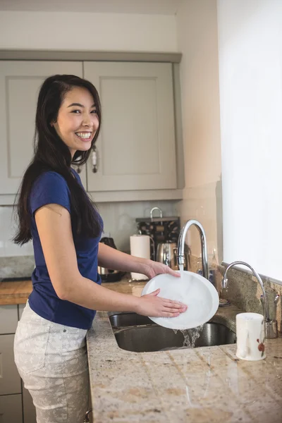 Mulher feliz lavando a louça na cozinha — Fotografia de Stock