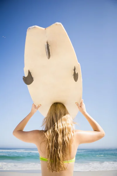 Woman holding surfboard over head — Stock Photo, Image