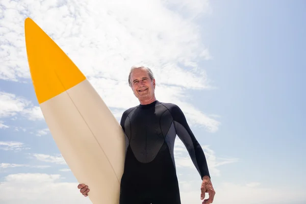 Старший человек в гидрокостюме, держащий доску для серфинга — стоковое фото