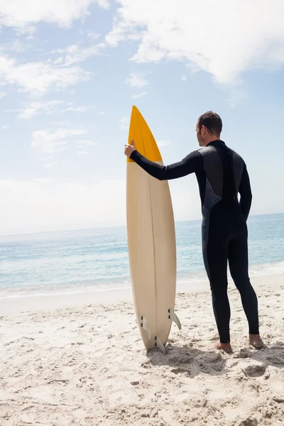 Hombre con tabla de surf de pie en la playa — Foto de Stock