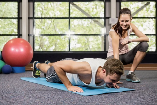 Entrenador ayudando al hombre con flexiones — Foto de Stock