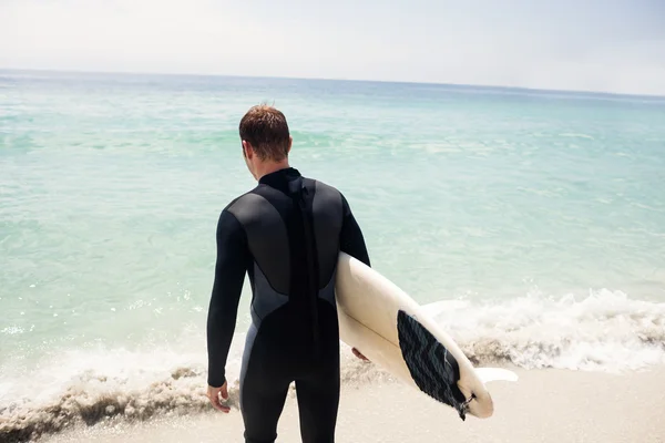 Surfer hält Surfbrett am Strand — Stockfoto
