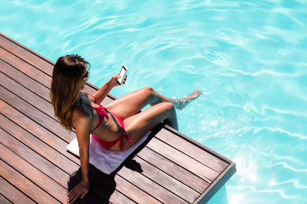 Woman using smartphone on pool edge — Stock Photo, Image