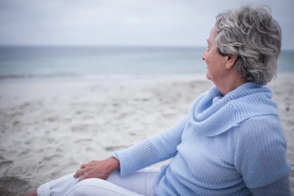 Задумчивая пожилая женщина на пляже — стоковое фото