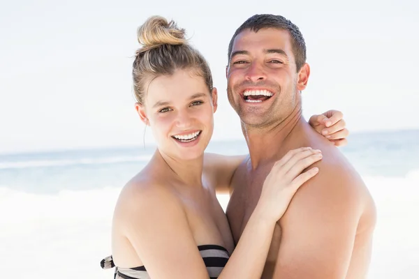 Lachende paar omarmen op het strand — Stockfoto