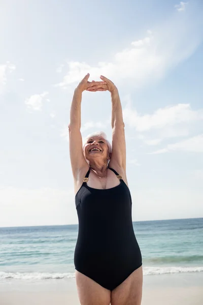 Senior woman stretching on beach — Stock Photo, Image