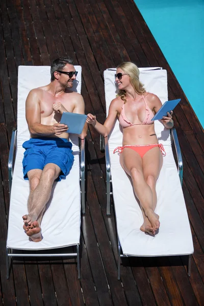 Couple utilisant une tablette couchée sur des transats — Photo