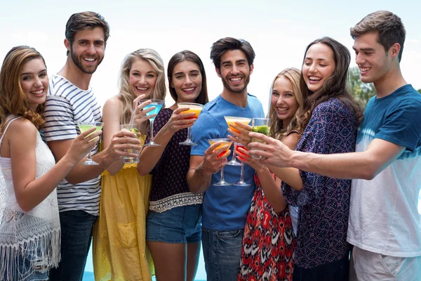 Grupo de amigos segurando um copo de coquetel perto da piscina — Fotografia de Stock