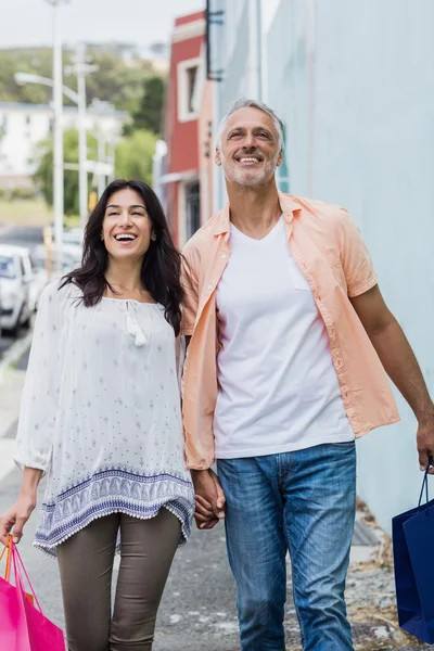 Lyckliga par promenader med kassar och påsar — Stockfoto