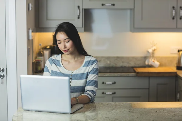 Γυναίκα που χρησιμοποιεί φορητό υπολογιστή στην κουζίνα — Φωτογραφία Αρχείου