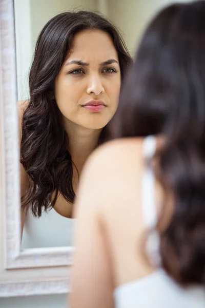 Woman looking in mirror of bathroom — Stock Photo, Image