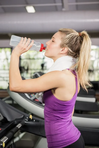 Frau auf Laufband trinkt Wasser im Fitnessstudio — Stockfoto