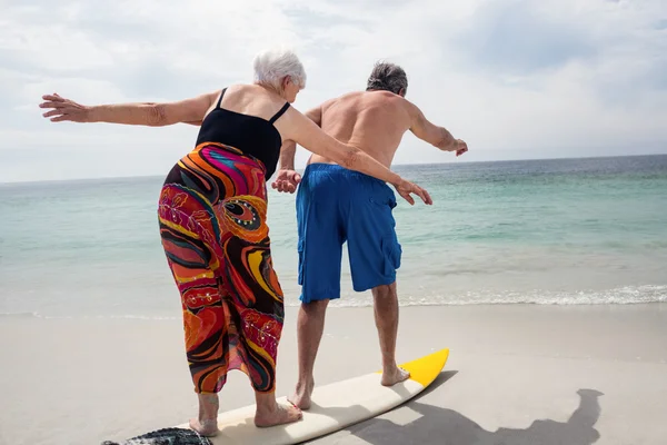 Старшая пара серфинга на пляже — стоковое фото