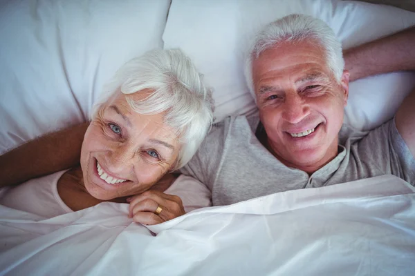Счастливая пожилая пара, лежащая на кровати — стоковое фото