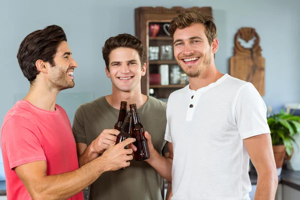 Sonriendo amigos masculinos tostando botellas de cerveza — Foto de Stock