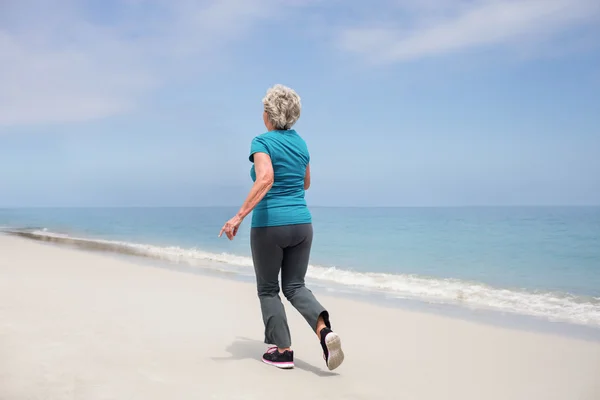 Senior vrouw joggen op strand — Stockfoto