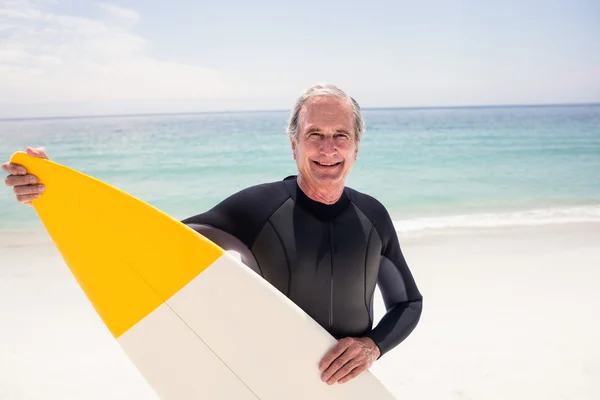 Uomo anziano in muta che tiene tavola da surf — Foto Stock