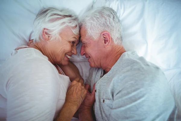 Coppia anziana toccare la testa mentre sdraiato sul letto — Foto Stock