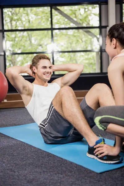 Tränare hjälpa mannen med buken crunches — Stockfoto