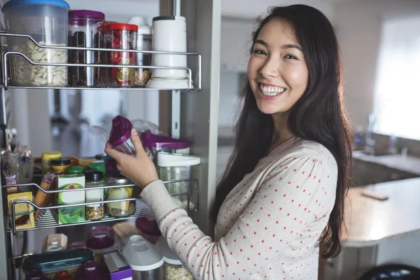 女人领料瓶从储存柜 — 图库照片