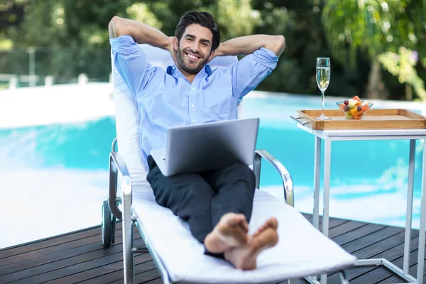 Slimme man met laptop op ligstoel — Stockfoto