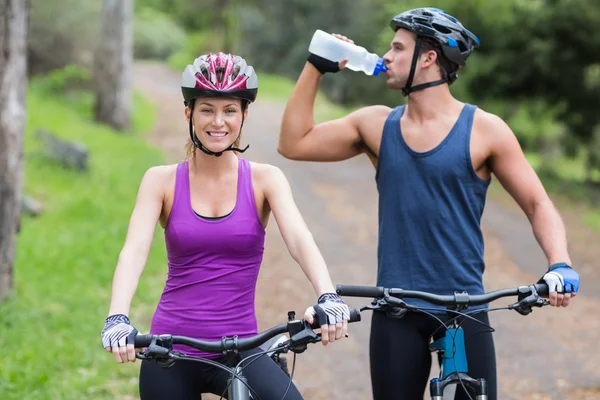 Biker drinking water by woman — Stock Photo, Image