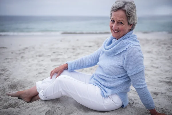 Mujer mayor sentada en la playa — Foto de Stock