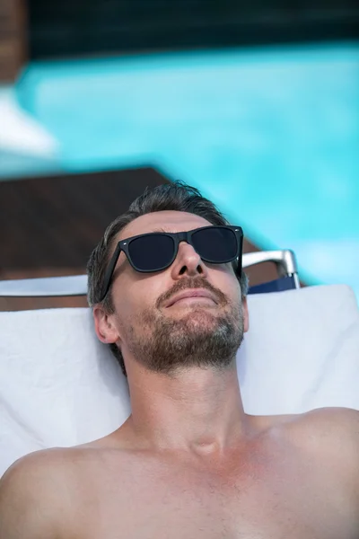 Beau homme en lunettes de soleil sur une chaise longue — Photo