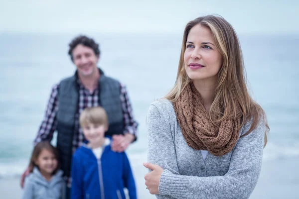 Donna in piedi contro la famiglia in spiaggia — Foto Stock