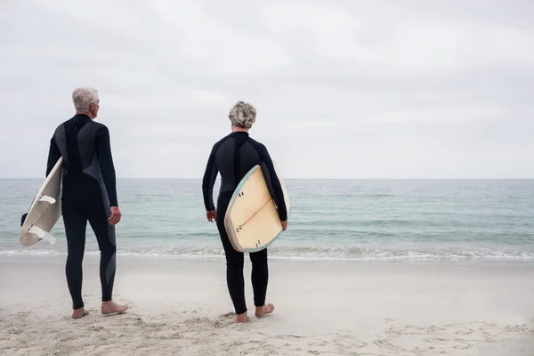 Par i våtdräkt holding surfbrädor — Stockfoto