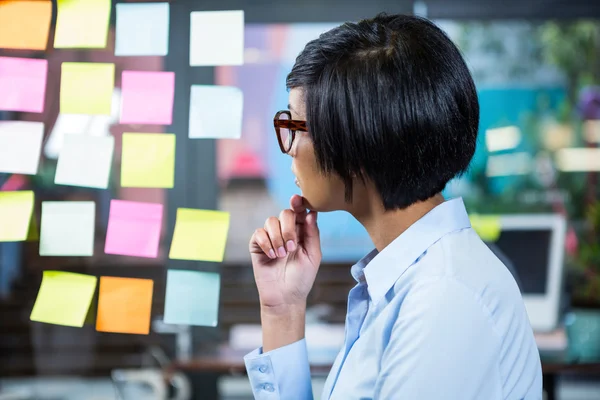 Mujer de negocios reflexiva mirando notas adhesivas —  Fotos de Stock