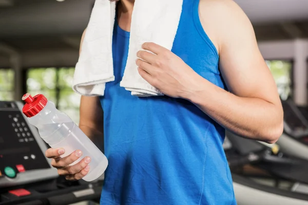 Uomo sul tapis roulant in possesso di bottiglia d'acqua — Foto Stock