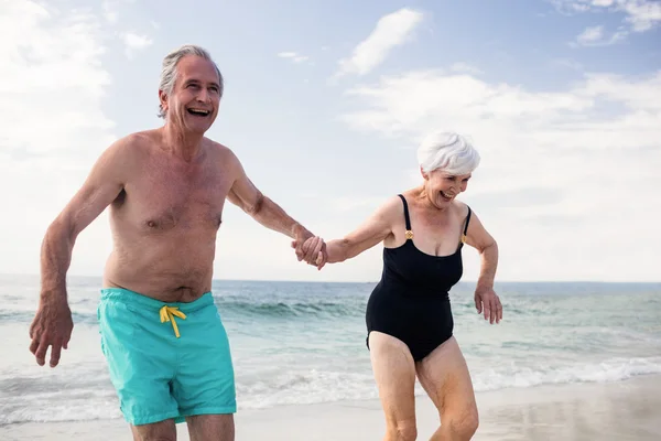 Äldre par kör på stranden — Stockfoto