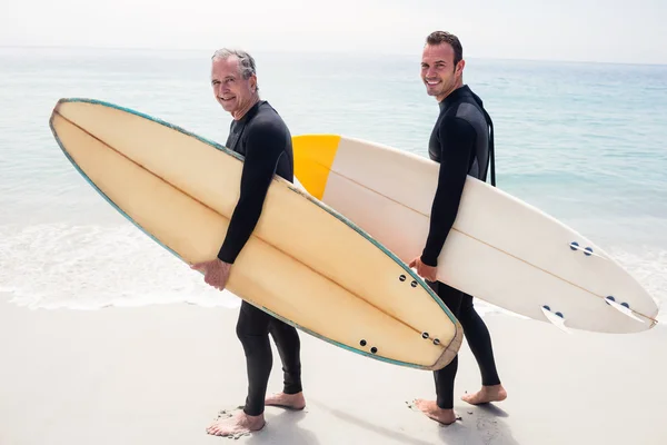 Padre e hijo en traje de neopreno sosteniendo tabla de surf — Foto de Stock