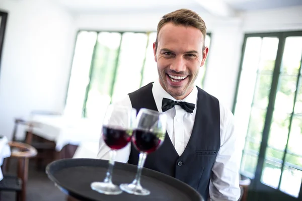 Garçom segurando bandeja com vinho tinto — Fotografia de Stock