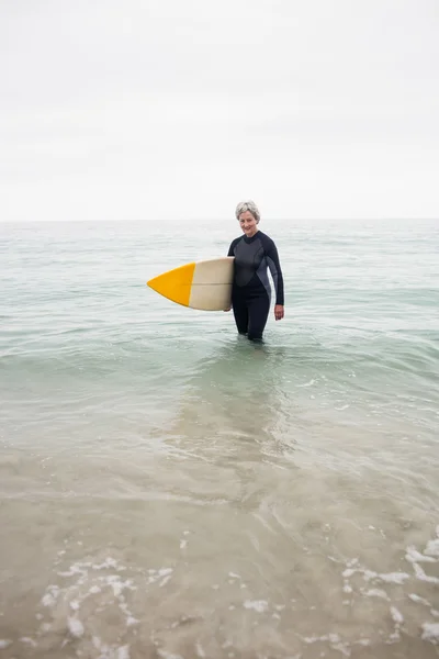Senior woman in water with surfboard — Stock Photo, Image