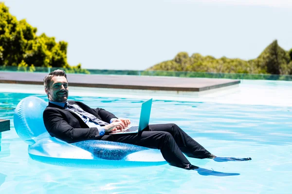 Businessman using laptop on inflatable — Stock Photo, Image