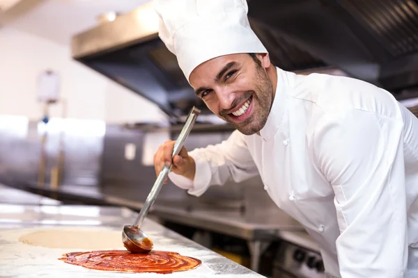 Pizza chef put sauce on base — Stock Photo, Image